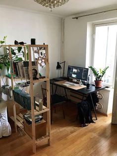 a room with a desk, computer and bookshelf filled with various items in it