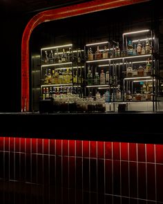 a dimly lit bar with bottles on the wall and red lights in the back ground