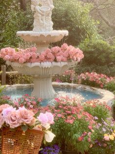 there is a fountain with pink flowers in the center and two baskets on the ground