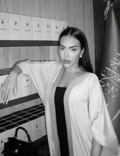 a black and white photo of a woman standing in front of lockers with her hand on her hip