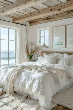 a white bed sitting in a bedroom next to an open window with curtains on it