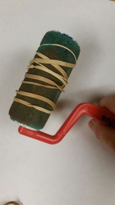 a person is painting a roll of paper with tape on it and a red handle