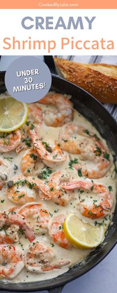 a skillet filled with shrimp and lemons on top of a table next to bread