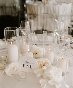 a table topped with lots of white flowers and candles