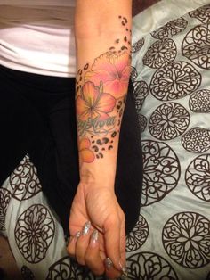 a woman with a flower tattoo on her arm holding the hand of another person's hand