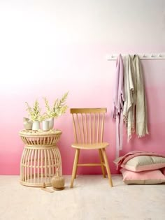 a pink room with two chairs and a plant on the table in front of it