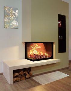 a fire place in the middle of a living room with wood logs on the floor