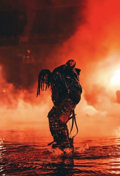 a man standing on top of a body of water in front of a red sky