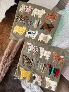 two pieces of fabric with animals on them sitting next to each other in front of a cow skin rug