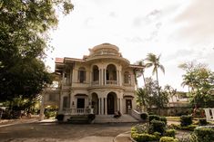 a large white house sitting in the middle of a lush green park with lots of trees