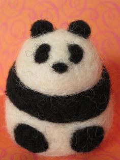 a stuffed panda bear sitting on top of an orange surface