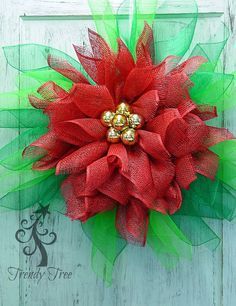 a red poinsettia wreath with green mesh and gold bells on the top