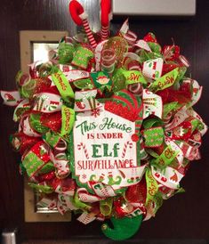 a christmas wreath with candy canes and ribbons hanging from it's front door