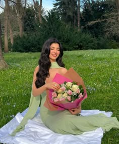 a woman sitting in the grass holding a bouquet of flowers