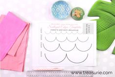 sewing supplies are laid out on top of a white table with pink and green fabric