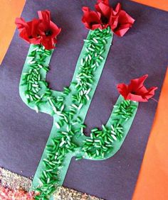 a cactus made out of paper on top of a piece of construction paper with red flowers