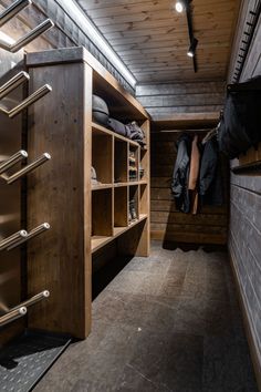 a closet with clothes hanging from the ceiling and wooden shelves on the wall next to it