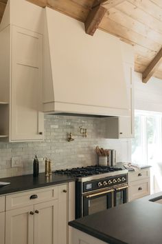 a kitchen with white cabinets, black counter tops and an oven in the center area