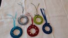 four crocheted ornaments are hanging on a white tablecloth with blue, green and red ribbons