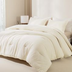 a large white bed sitting in a bedroom next to a window