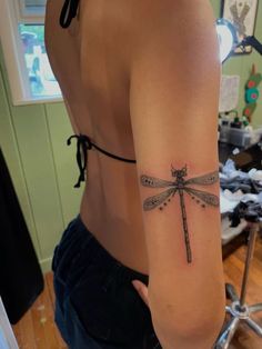 a woman's arm with a tattoo on it that has a dragonfly on it