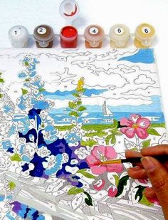 someone is painting flowers on a piece of paper with watercolors in front of them