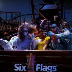 a group of people dressed up as zombies in front of a roller coaster at night