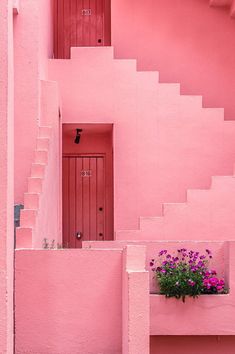 a pink building with flowers in the window box and stairs leading up to the door