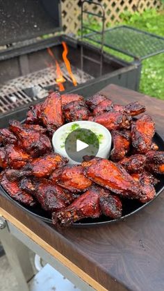 a plate full of chicken wings on top of a table next to an open fire pit