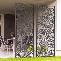 an outdoor room divider with palm leaves on it and chairs in the back yard