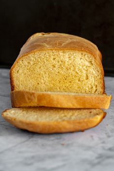 a loaf of bread sitting on top of a counter next to a slice of bread