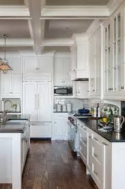 a large kitchen with white cabinets and black counter tops, along with hardwood floors in the center