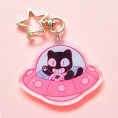 a pink keychain with a black cat on it and a star in the background