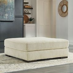 a white ottoman sitting on top of a rug in a living room next to a doorway