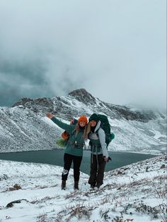 two people standing on top of a snow covered hill