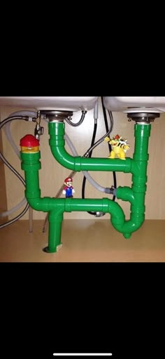 a sink with two green pipes connected to the faucet and some toy figures