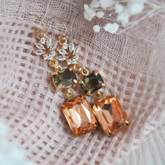 two pairs of earrings sitting on top of a piece of cloth