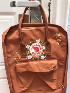 an orange bag with flowers on it hanging from a door handle