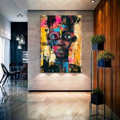 an abstract painting hangs on the wall next to a table with chairs and potted plants