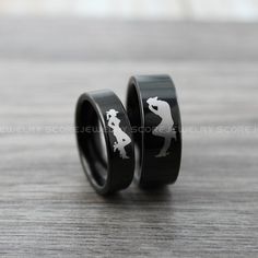 two black rings with white designs on them sitting on top of a wooden table next to each other