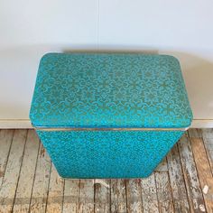 a blue box sitting on top of a wooden floor next to a white wall and wood floor