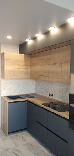 an empty kitchen with blue cabinets and white marble counter tops, under recessed lighting