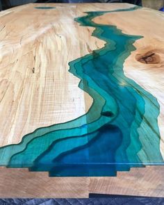 a table made out of wood with blue water flowing down the center and on top