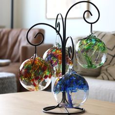 three glass ornaments sitting on top of a wooden table next to a brown couch in a living room