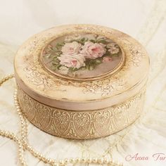 an antique box with flowers painted on the lid is sitting on a white tablecloth