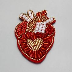 a red heart shaped brooch with pearls and bows