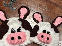 two crocheted cow hats are laying on the floor