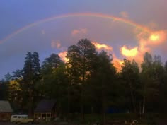 a rainbow is shining in the sky over some trees