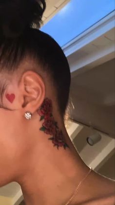 a woman with a tattoo on her neck and behind her ear is looking into the distance