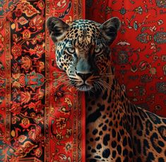 a leopard sitting on top of a rug next to a red wall with ornate designs